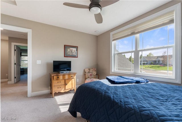 bedroom featuring light carpet, baseboards, and a ceiling fan