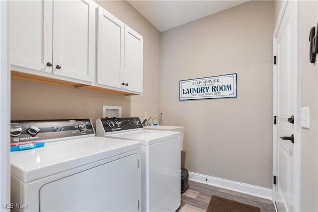 laundry room with cabinet space, washing machine and clothes dryer, wood finished floors, and baseboards