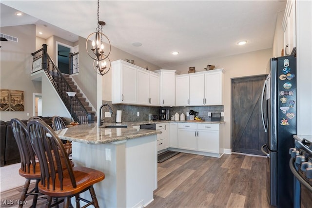 kitchen featuring a peninsula, a breakfast bar area, a sink, white cabinetry, and appliances with stainless steel finishes