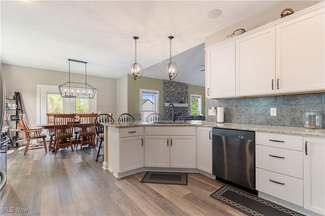 kitchen featuring a peninsula, wood finished floors, white cabinets, stainless steel dishwasher, and decorative backsplash