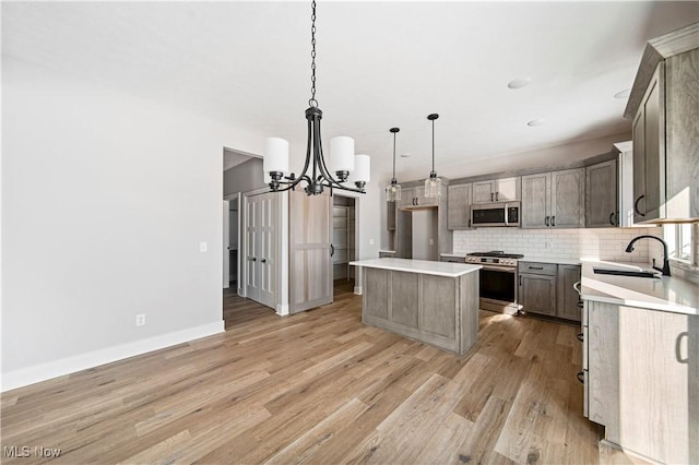 kitchen featuring a sink, stainless steel appliances, light wood-style floors, a chandelier, and tasteful backsplash