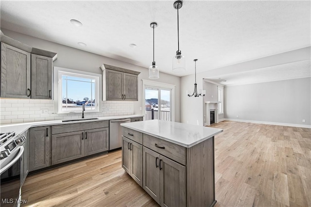 kitchen with a sink, open floor plan, light wood-style floors, stainless steel appliances, and tasteful backsplash
