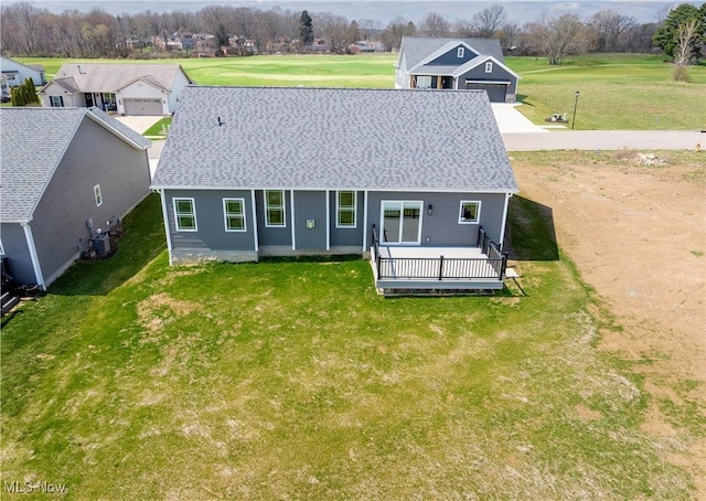 back of house featuring a lawn and roof with shingles