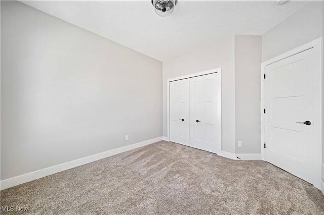 unfurnished bedroom with carpet, a closet, and baseboards