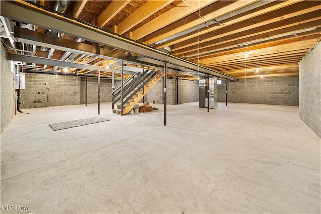 unfinished basement with stairway, heating unit, and concrete block wall