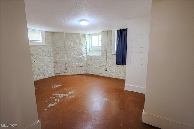 below grade area featuring a textured ceiling and a healthy amount of sunlight
