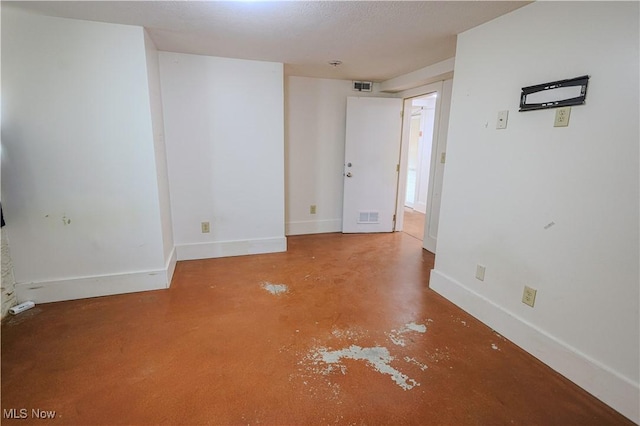 empty room featuring finished concrete floors, visible vents, and baseboards