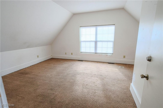 additional living space featuring lofted ceiling, baseboards, visible vents, and carpet floors