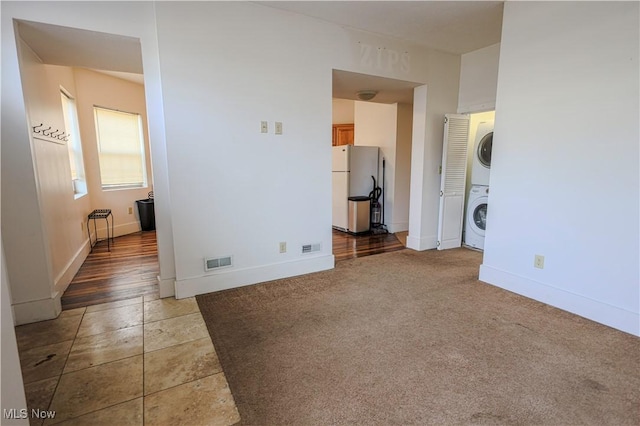spare room with stacked washer and dryer, baseboards, and visible vents