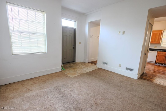 foyer featuring light colored carpet, baseboards, and visible vents
