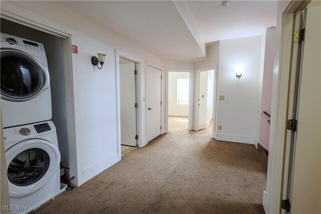 clothes washing area featuring carpet, stacked washing maching and dryer, baseboards, and laundry area