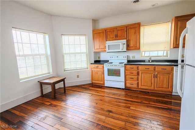 kitchen featuring baseboards, white appliances, dark countertops, and dark wood-style floors