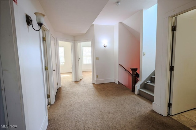 hallway featuring carpet flooring, baseboards, and an upstairs landing