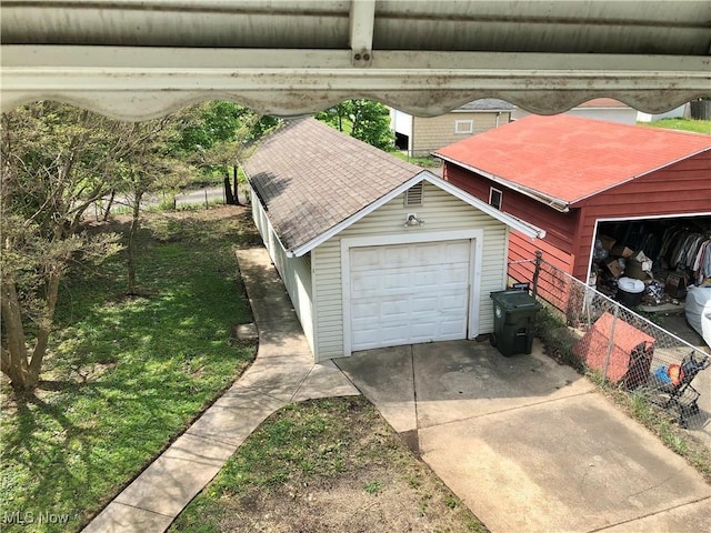 garage with concrete driveway and fence
