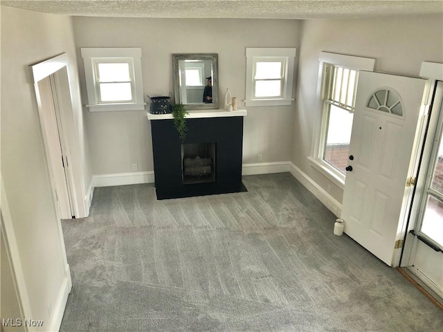 unfurnished living room with baseboards, carpet flooring, and a textured ceiling