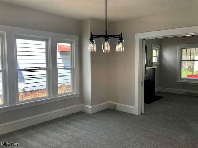 unfurnished dining area featuring an inviting chandelier, carpet, baseboards, and visible vents