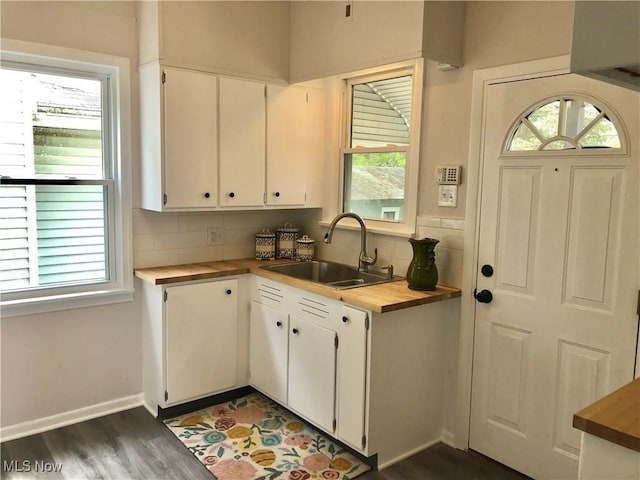 kitchen featuring butcher block counters, tasteful backsplash, a sink, and white cabinets