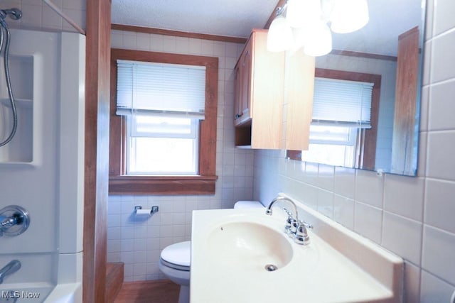 bathroom with tile walls, shower / bathtub combination, toilet, and plenty of natural light