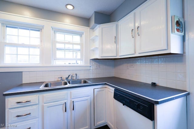 kitchen featuring a sink, dark countertops, white cabinetry, decorative backsplash, and white dishwasher