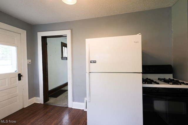 kitchen with range with gas stovetop, dark wood-type flooring, freestanding refrigerator, and baseboards