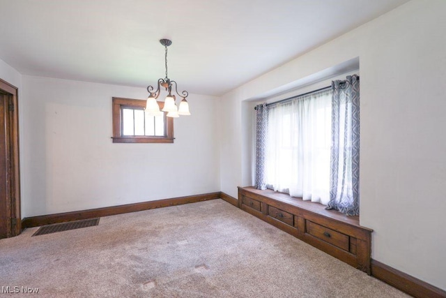 spare room with a chandelier, carpet flooring, baseboards, and visible vents