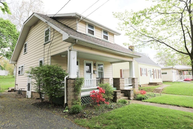 bungalow-style house with a front yard, a porch, and roof with shingles