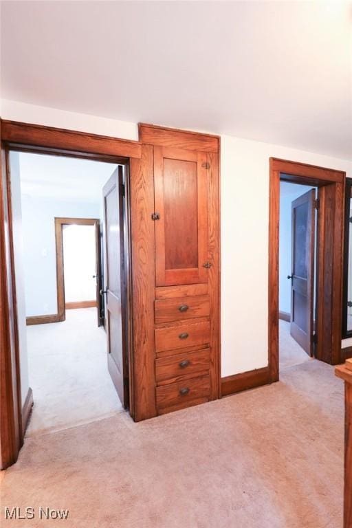 corridor with baseboards and light carpet