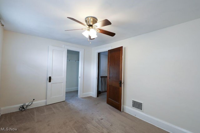 interior space featuring light colored carpet, baseboards, a ceiling fan, and visible vents