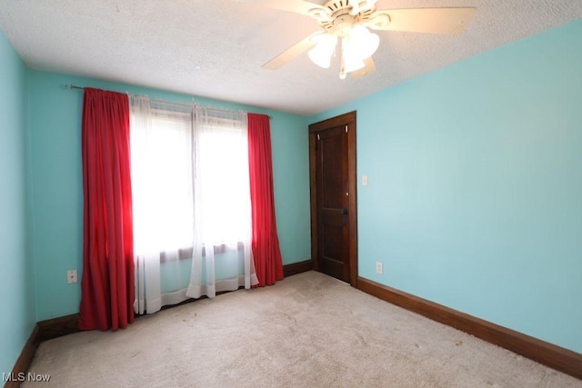 carpeted empty room featuring a ceiling fan, baseboards, and a textured ceiling