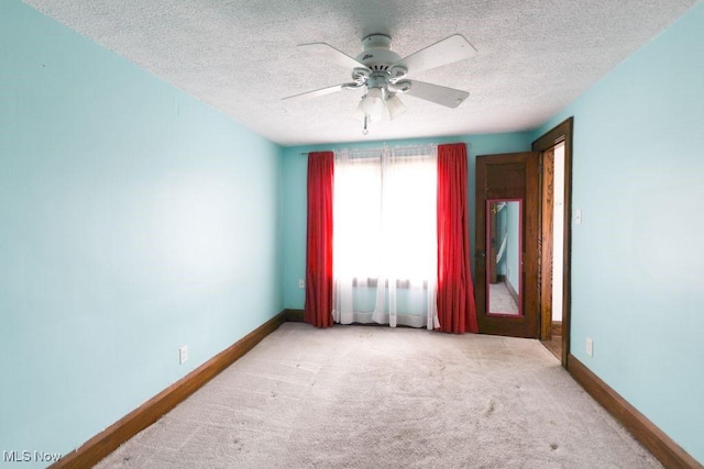 carpeted empty room with baseboards, ceiling fan, and a textured ceiling