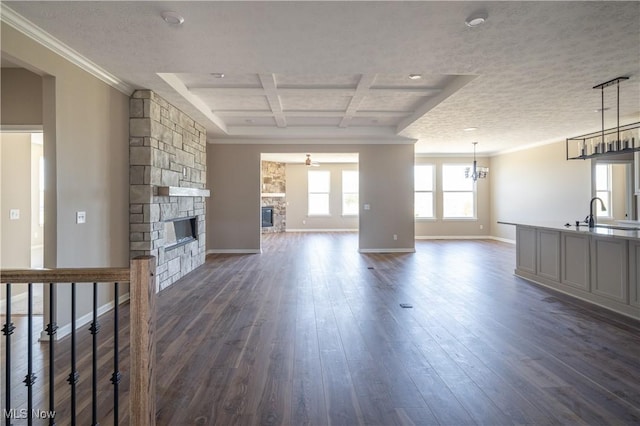 unfurnished living room featuring ornamental molding, dark wood finished floors, baseboards, and a stone fireplace