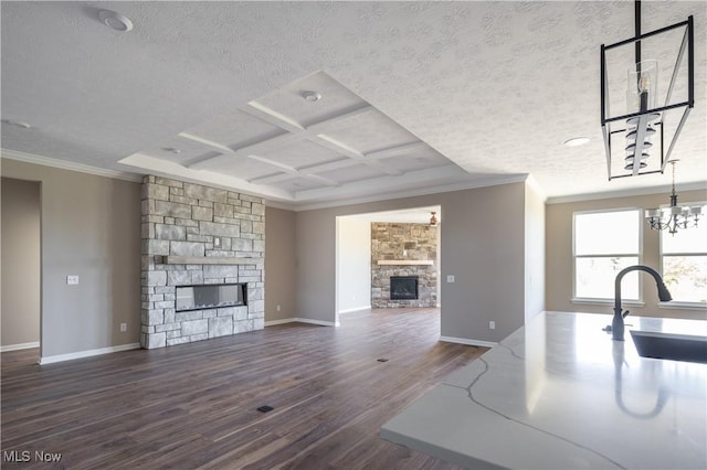 unfurnished living room featuring wood finished floors, a sink, baseboards, a stone fireplace, and ornamental molding
