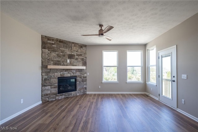 unfurnished living room with dark wood finished floors, baseboards, a ceiling fan, and a textured ceiling
