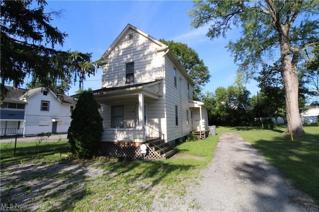view of front of property featuring covered porch, a front lawn, and fence