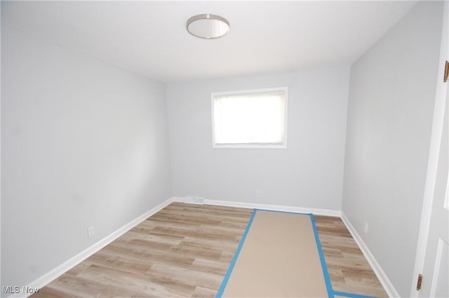 unfurnished room with baseboards and light wood-style floors