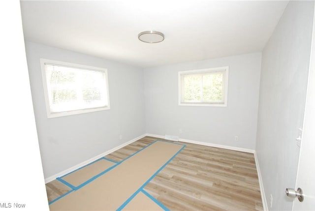 spare room featuring baseboards and wood finished floors