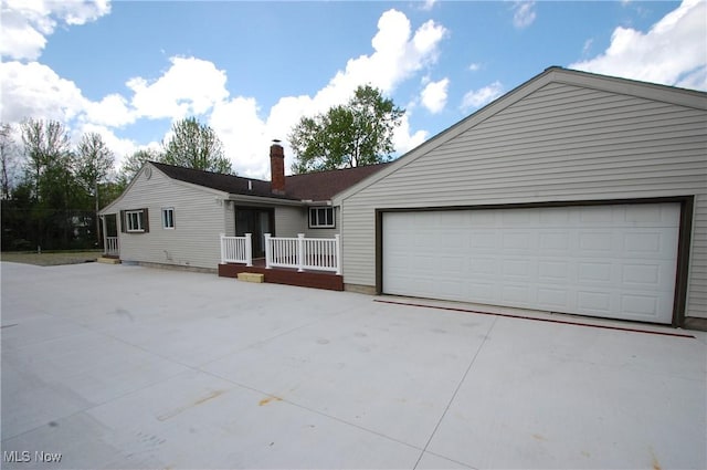 single story home with concrete driveway, a chimney, and a garage