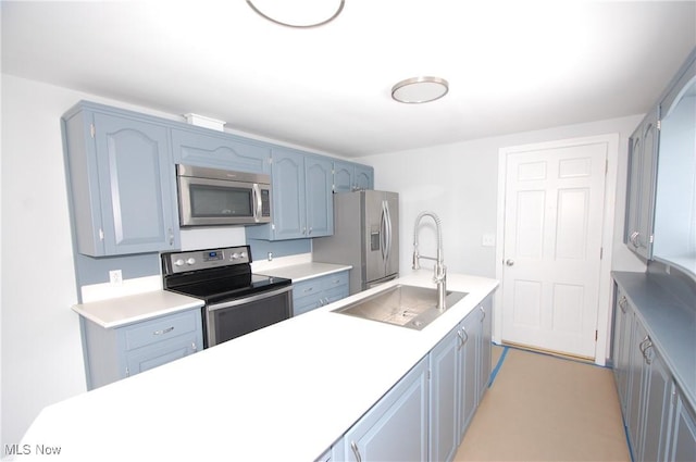 kitchen with a sink, blue cabinets, light countertops, and appliances with stainless steel finishes