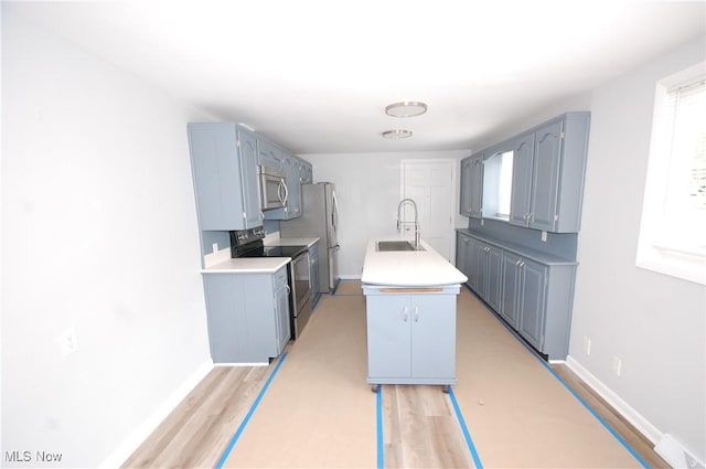 kitchen with a sink, light countertops, a center island with sink, and appliances with stainless steel finishes