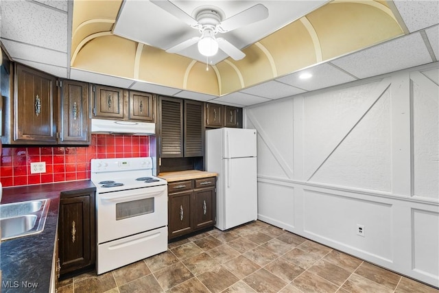 kitchen with white appliances, tasteful backsplash, under cabinet range hood, dark brown cabinetry, and ceiling fan