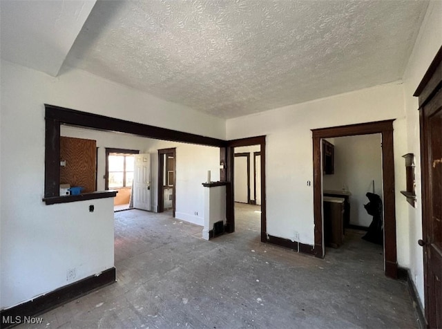 empty room with a textured ceiling and baseboards