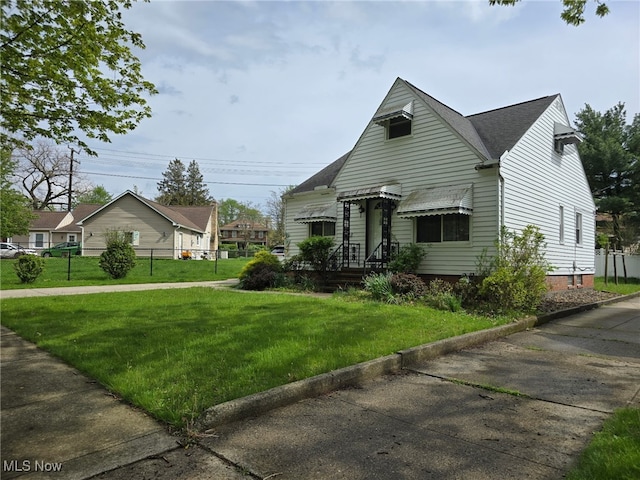 view of front of home featuring roof with shingles, fence, and a front yard