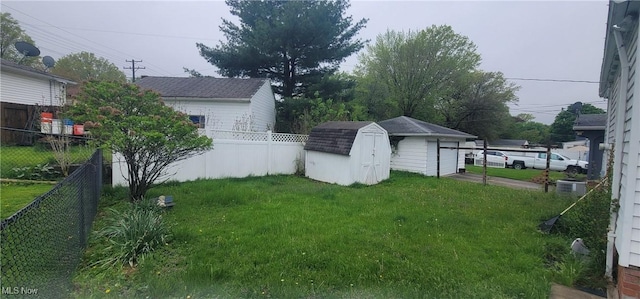 view of yard with an outdoor structure, a detached garage, central AC unit, a fenced backyard, and a storage unit