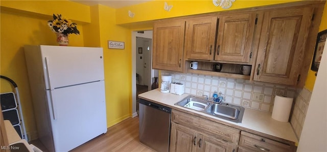 kitchen featuring a sink, tasteful backsplash, freestanding refrigerator, light countertops, and stainless steel dishwasher