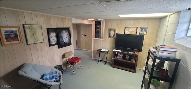 living area featuring wooden walls, concrete flooring, and a paneled ceiling