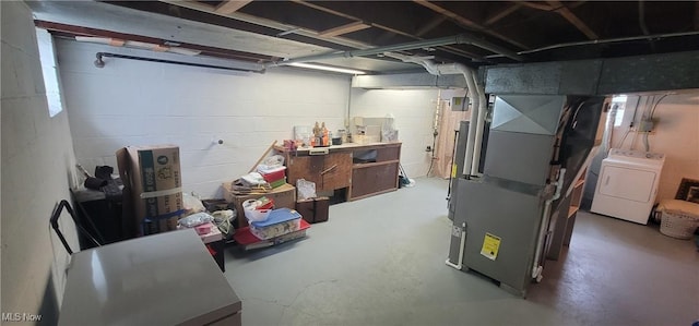 basement featuring washer / dryer, concrete block wall, and heating unit