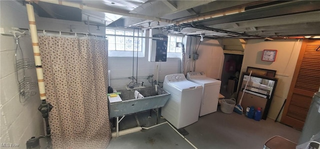 basement featuring a sink, concrete block wall, and washer and clothes dryer