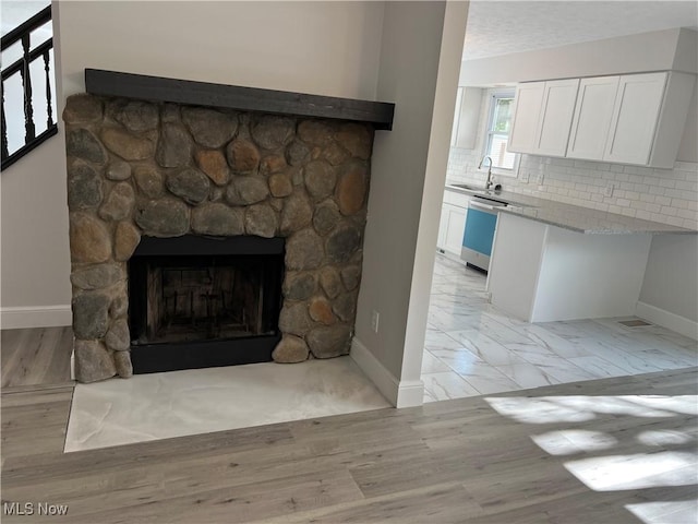 1279 Lander Rd, Mayfield Heights, OH 44124 - details with baseboards, a stone fireplace, a sink, dishwashing machine, and backsplash