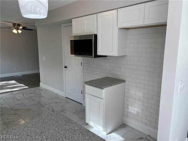1279 Lander Rd, Mayfield Heights, OH 44124 - kitchen with white cabinets, tile walls, baseboards, ceiling fan, and marble finish floor