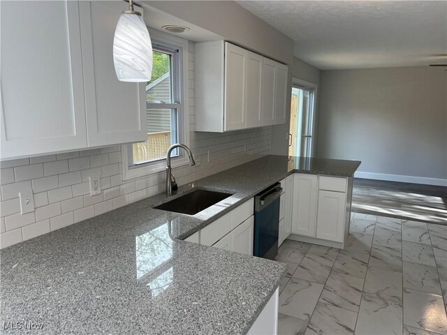 1279 Lander Rd, Mayfield Heights, OH 44124 - kitchen featuring a sink, a peninsula, dishwashing machine, white cabinetry, and stone counters